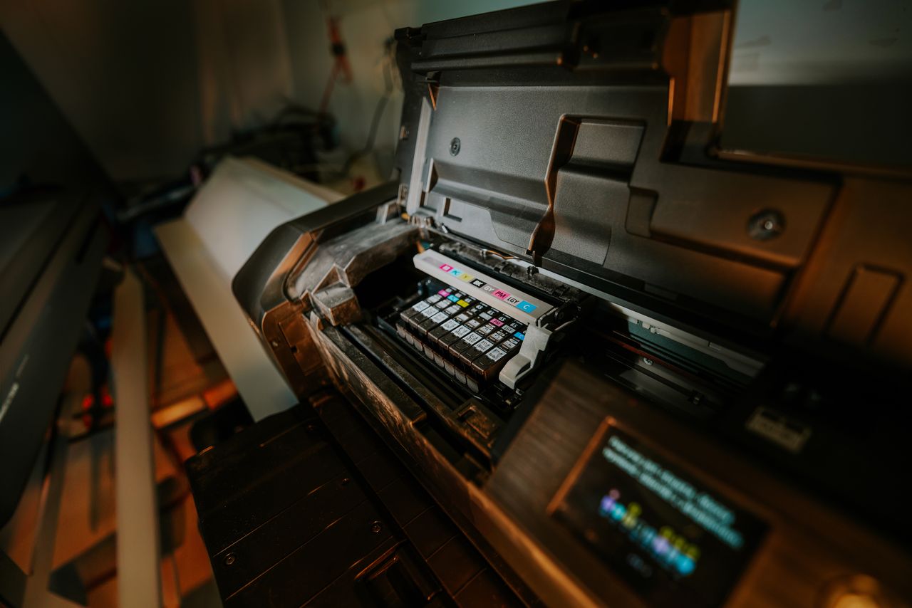 The Art of Drawing Readers In: Your attractive post title goes here Close-up view of an inkjet printer with exposed cartridges in a workspace setting.